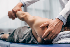 selective focus of chiropractor stretching arm of patient in hospital